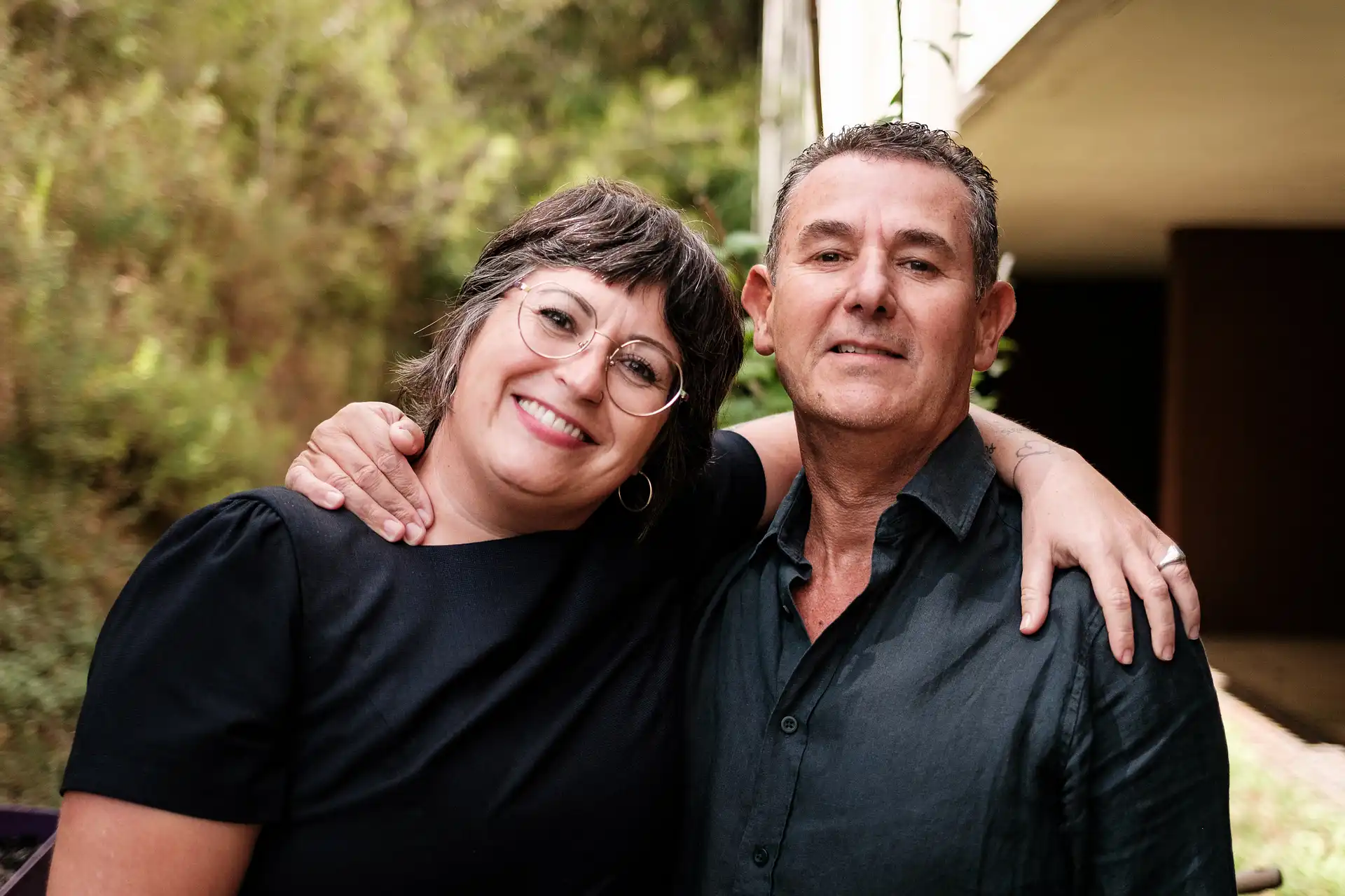 Una pareja sonríe juntos, con el hombre con el brazo alrededor de la mujer.