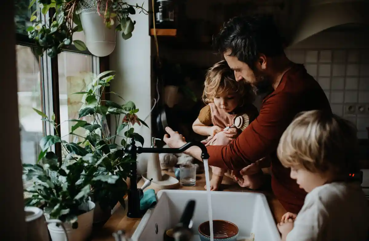 Un padre con sus dos hijos en la cocina