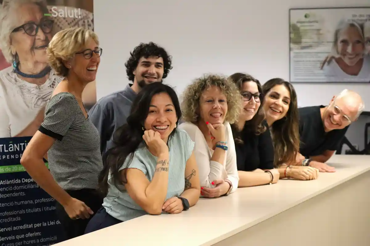 Un grupo de personas sonríe y posa juntos en un escritorio.